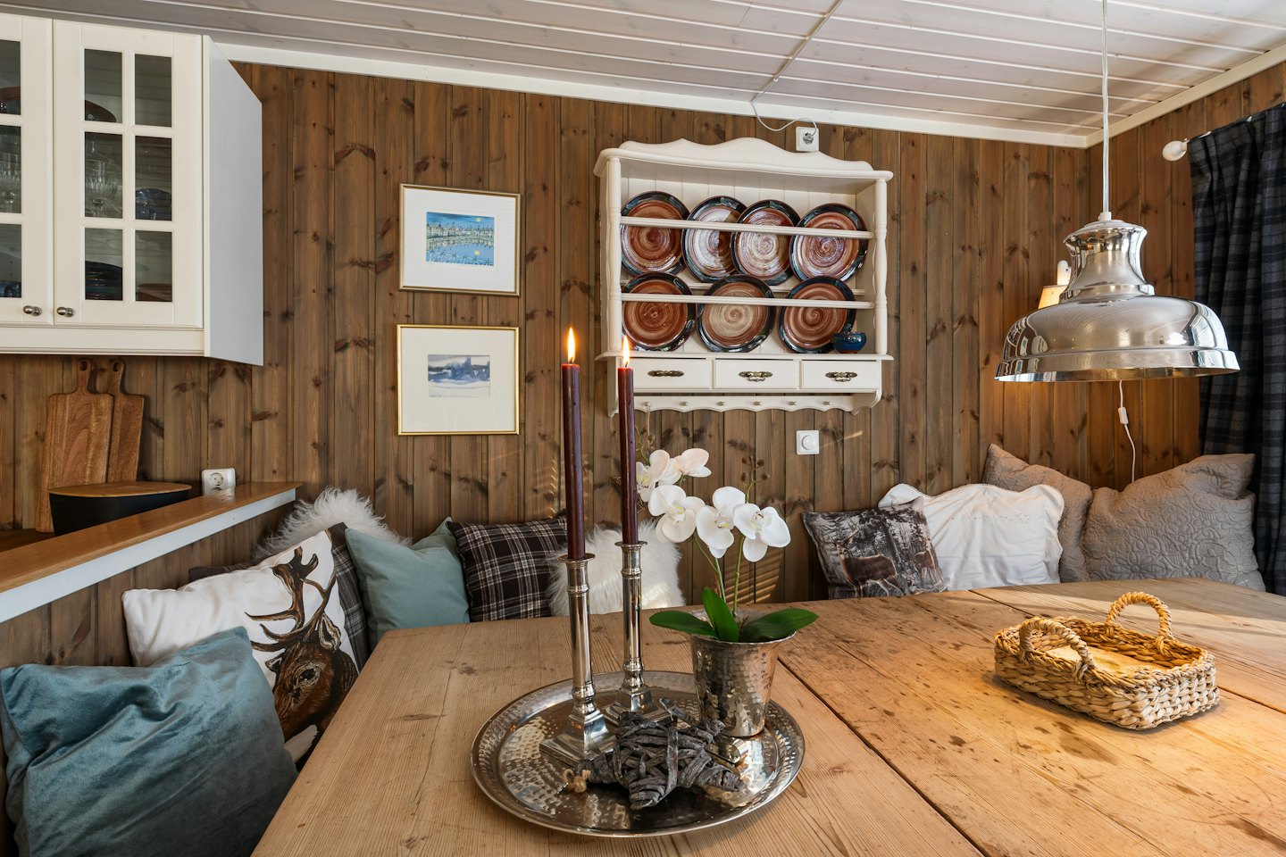 Un angolo pranzo rustico con tavolo in legno e cuscini decorativi.