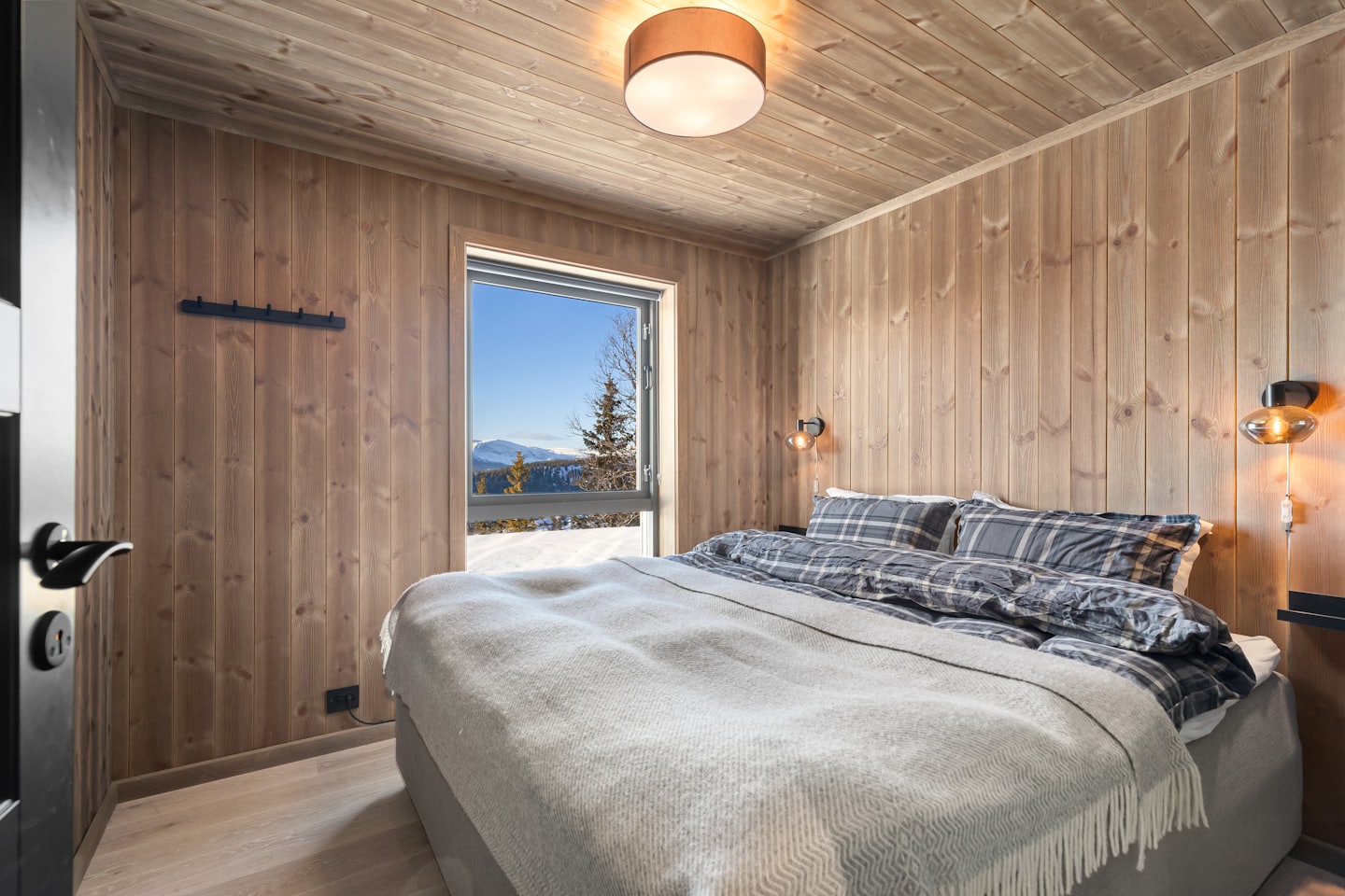 Una camera da letto accogliente si affaccia su un paesaggio montano innevato attraverso una finestra.